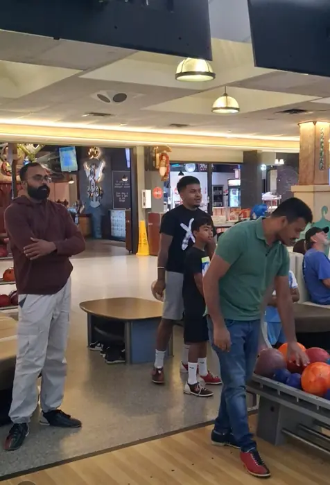 Members bowling together, with a young boy waiting for his turn