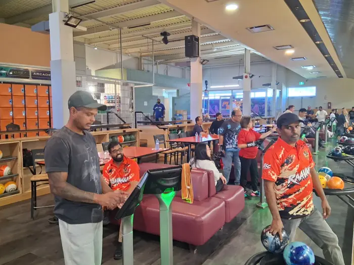 Members in orange Raavanaa jerseys, one holding his ball ready to bowl
