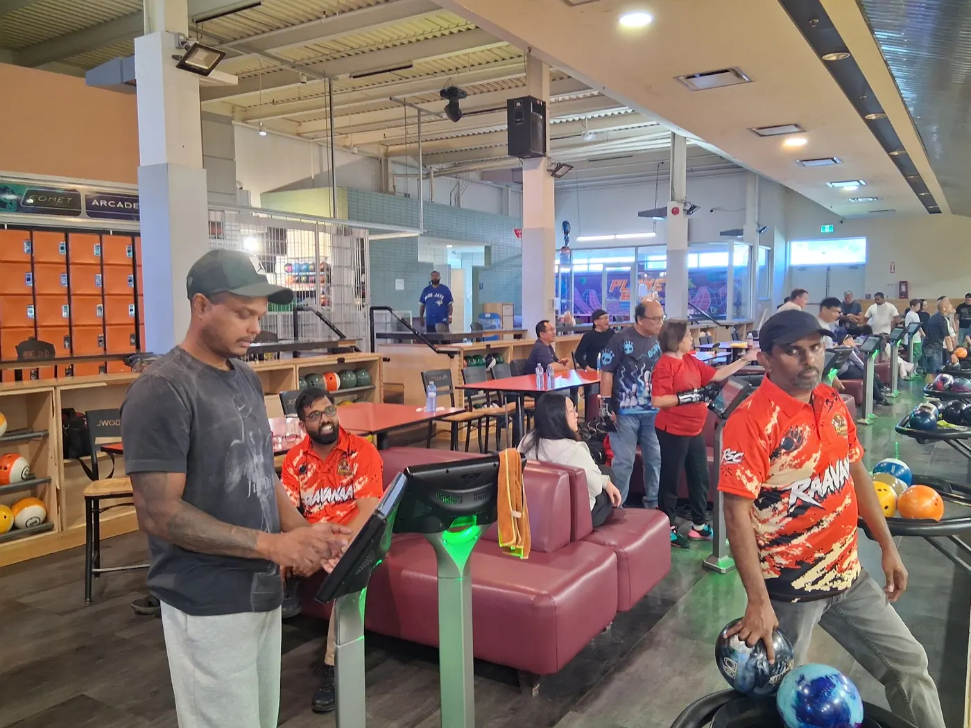 Members in orange Raavanaa jerseys, one holding his ball ready to bowl